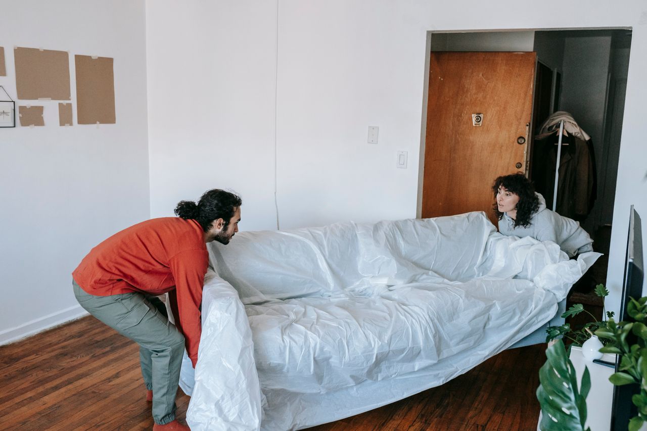 A couple working together to carry a couch into a new apartment during a move.